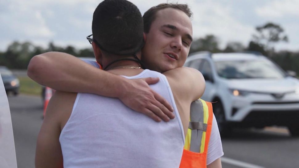 Garrett Popovich (in orange vest) hugs Alex Morales after pulling him out of his sinking vehicle Thursday. (Orlando Fire Department)