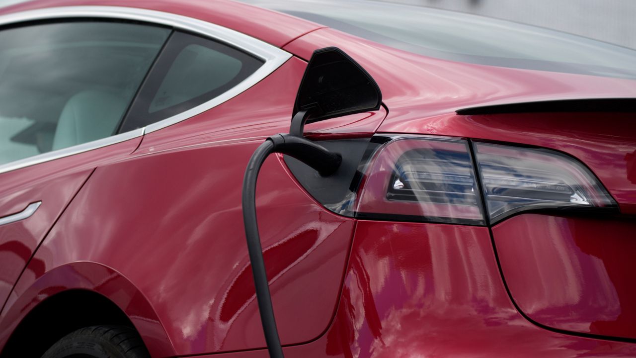 In this Sunday, June 27, 2021, photograph, a 2021 Model 3 sedan charges as it sits in a near-empty lot at a Tesla dealership in Littleton, Colo. (AP Photo/David Zalubowski)