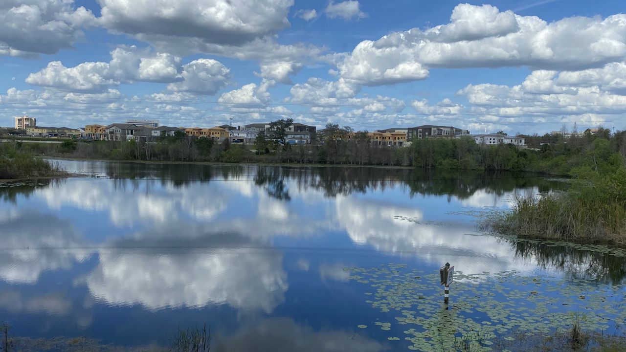 The partly cloudy sky is mirrored in a glassy lake in the Dr. Phillips neighborhood of Orange County on Sunday afternoon. (Karen Lary/viewer)