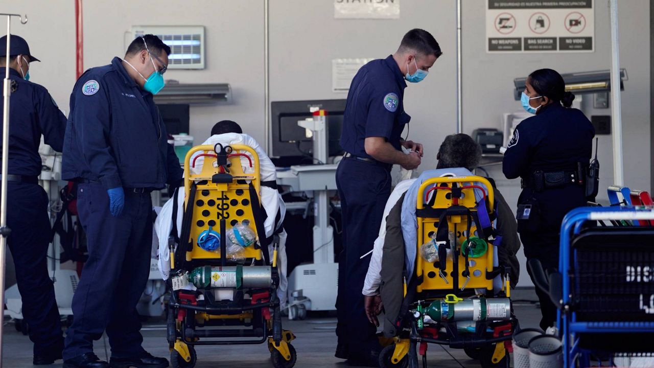 Los Angeles County emergency medical technicians deliver patients for admission at the Ambulatory Care Center station at the MLK Community Medical Group hospital in Los Angeles, Feb. 24, 2021. (AP Photo/Damian Dovarganes, File)