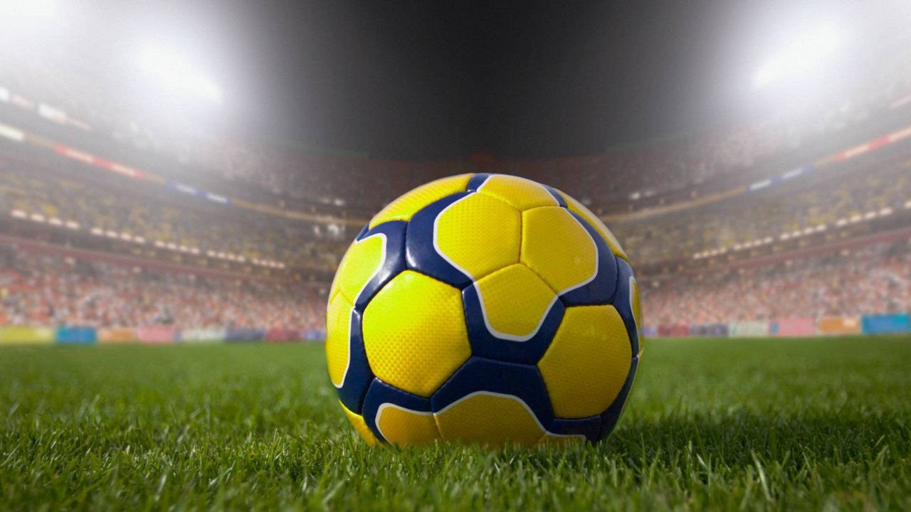 close-up of a yellow and blue soccer ball in a crowded stadium at night