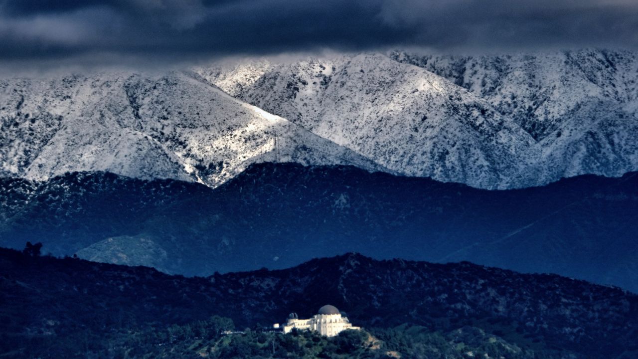 Storm clouds and snow are seen over the San Gabriel mountain range behind Griffith Observatory in the Hollywood Hills part of Los Angeles on Sunday, Feb. 26, 2023. (AP Photo/Richard Vogel)