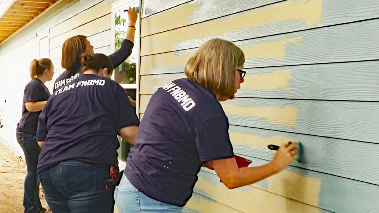 Volunteers with Habitat for Humanity paint a house in this file image. (Spectrum News/FILE)