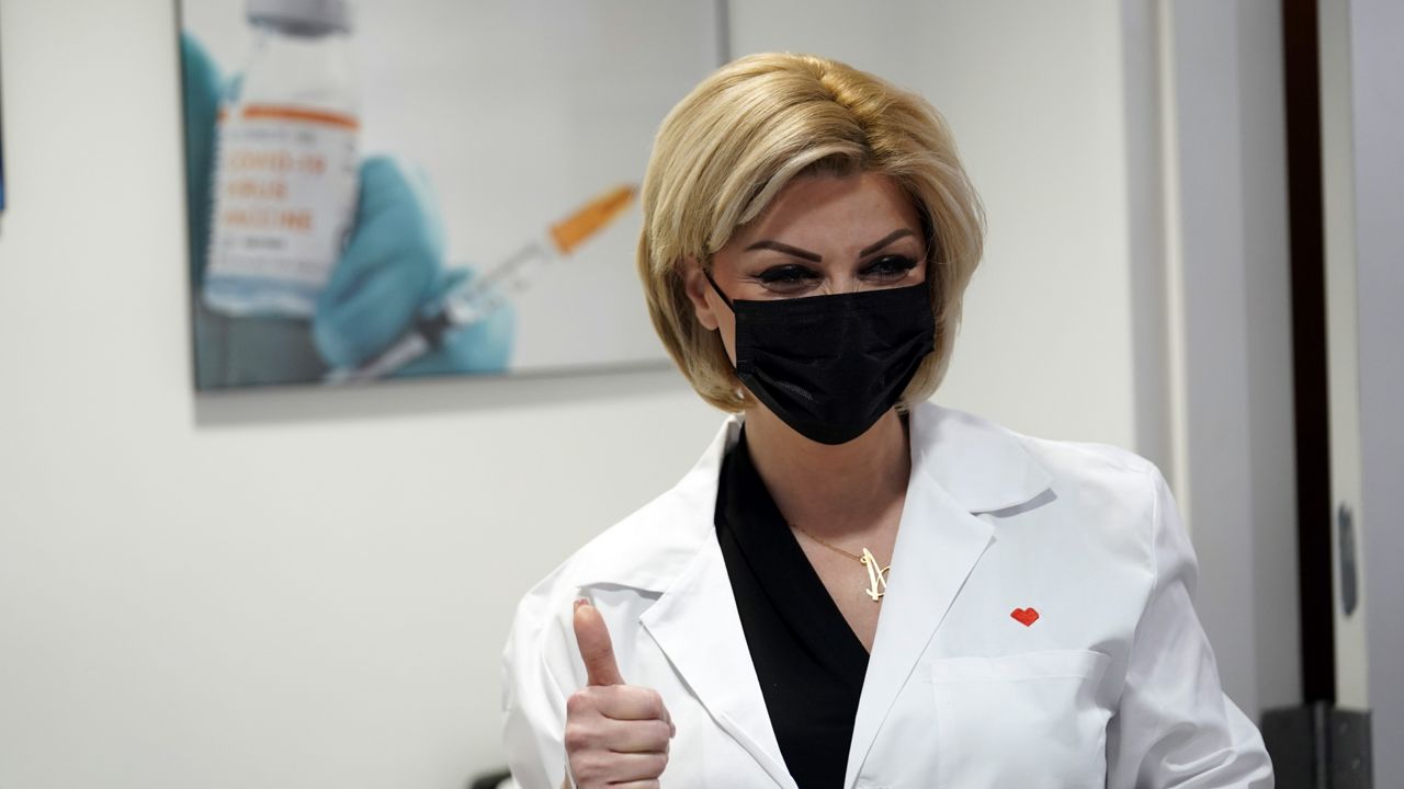 Pharmacy technician Ani Stepanian gives a thumbs up as she administers the Moderna COVID-19 vaccine at a CVS Pharmacy branch Monday, March 1, 2021, in Los Angeles. (AP Photo/Marcio Jose Sanchez)