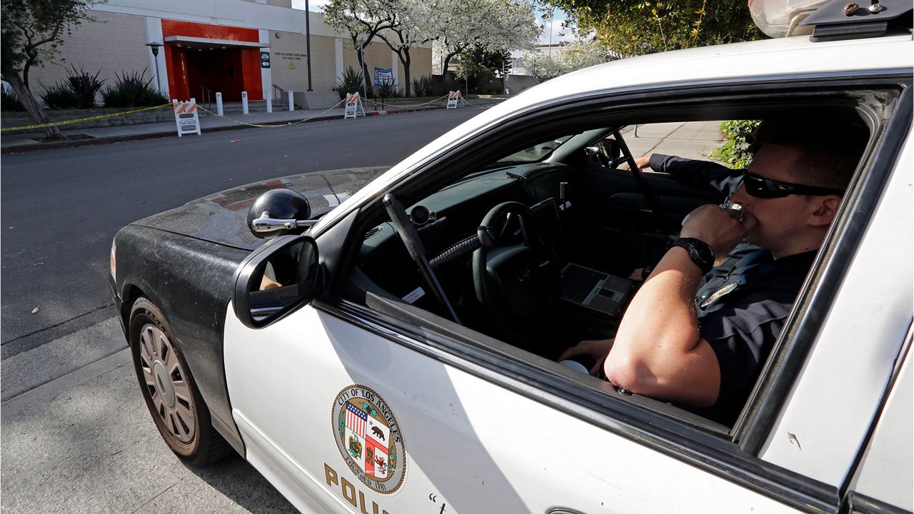 Officers in a patrol car keep watch in front of the West Los Angeles police station, Feb. 8, 2013. (AP Photo/Reed Saxon)