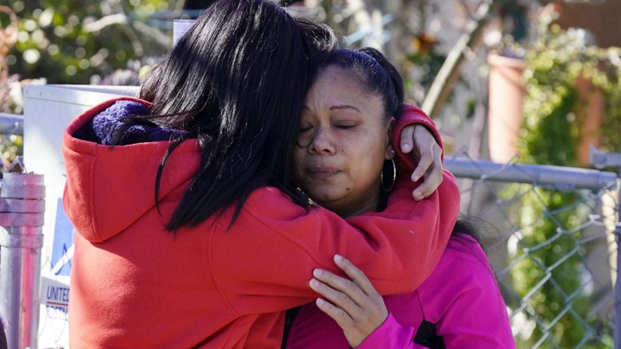 Ana DeJesus, right, is comforted by her daughter, Lizbeth DeJesus after placing a teddy bear and flowers on a memorial at The Church in Sacramento, Calif., on Tuesday, March 1, 2022. (AP Photo/Rich Pedroncelli)