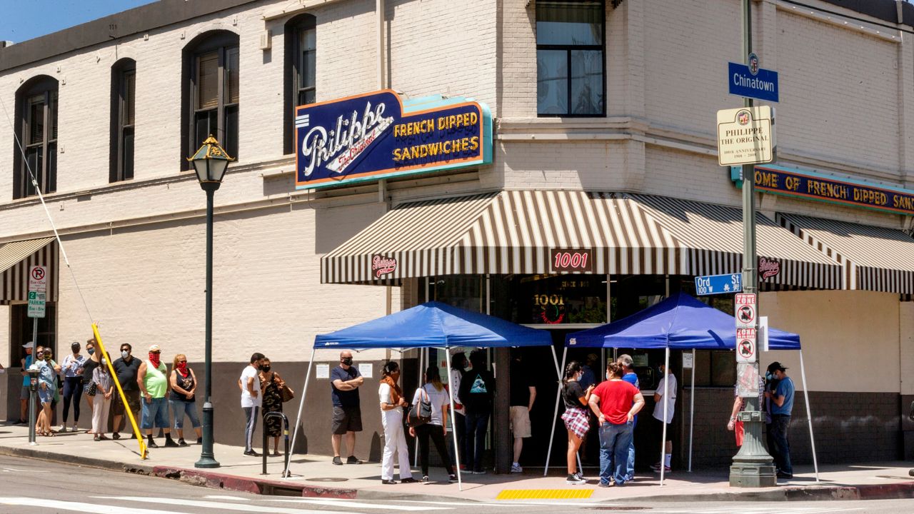 In this Saturday, May 2, 2020 file photo people stand in line while following social distancing guidelines as they wait for French dip sandwiches outside Philippe the Original restaurant in downtown Los Angeles. May 1, 2020 file photo (AP Photo/Damian Dovarganes,File)