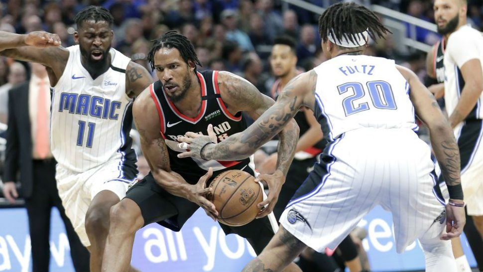 Portland Trail Blazers forward Trevor Ariza, center, drives between Orlando Magic forward James Ennis III (11) and guard Markelle Fultz (20) during the first half of an NBA basketball game, Monday, March 2, 2020, in Orlando, Fla. (AP Photo/John Raoux)