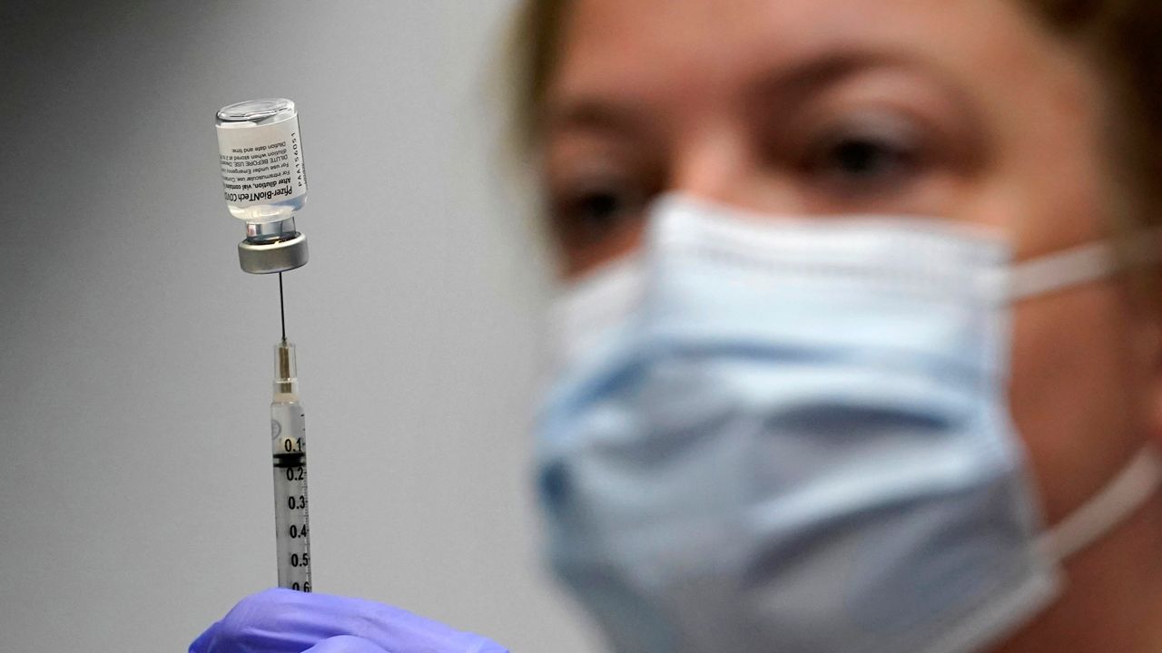 vaccine vial is loaded into a syringe by a health care worker