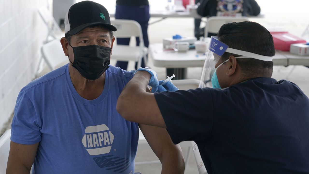 Farmworker Francisco Quintana, left, receives a Moderna COVID-19 vaccine at a County of Santa Clara mobile vaccination clinic at Monterey Mushrooms, an agricultural employer under the United Farm Workers union contract, amid the coronavirus pandemic in Morgan Hill, Calif., Wednesday, March 3, 2021. (AP Photo/Jeff Chiu)