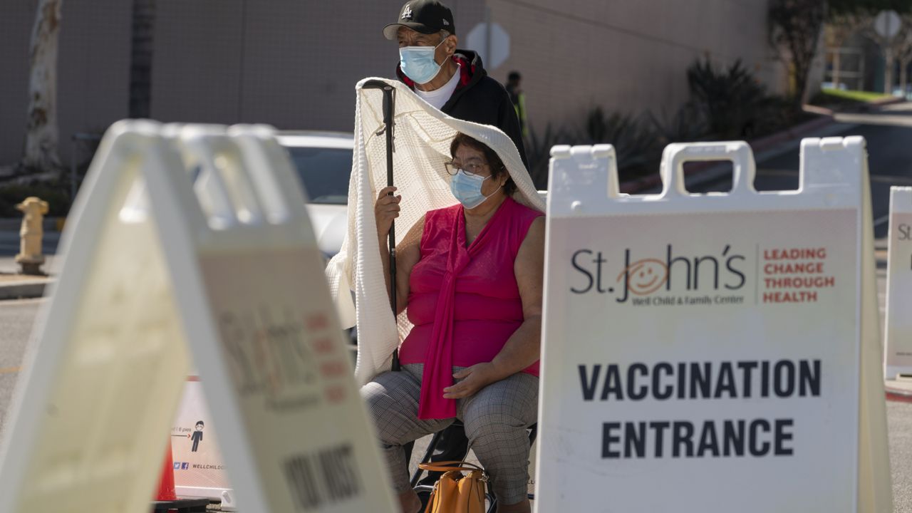 Jose Rosas and his wife, Sara, who live in the 90060 zip code, wait in line to be screened for high temperatures before being vaccinated at the St. John's Well Child and Family Center COVID-19 vaccination site at the East Los Angeles Civic Center in Los Angeles, Thursday, March 4, 2021. (AP Photo/Damian Dovarganes)