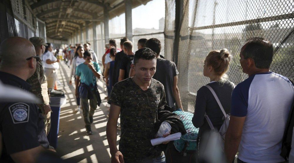 In this Aug. 2, 2019 file photo, migrants return to Mexico as other migrants line up on their way to request asylum in the U.S., at the foot of the Puerta Mexico bridge in Matamoros, Mexico, that crosses into Brownsville, Texas.  (AP Photo/Emilio Espejel, File)