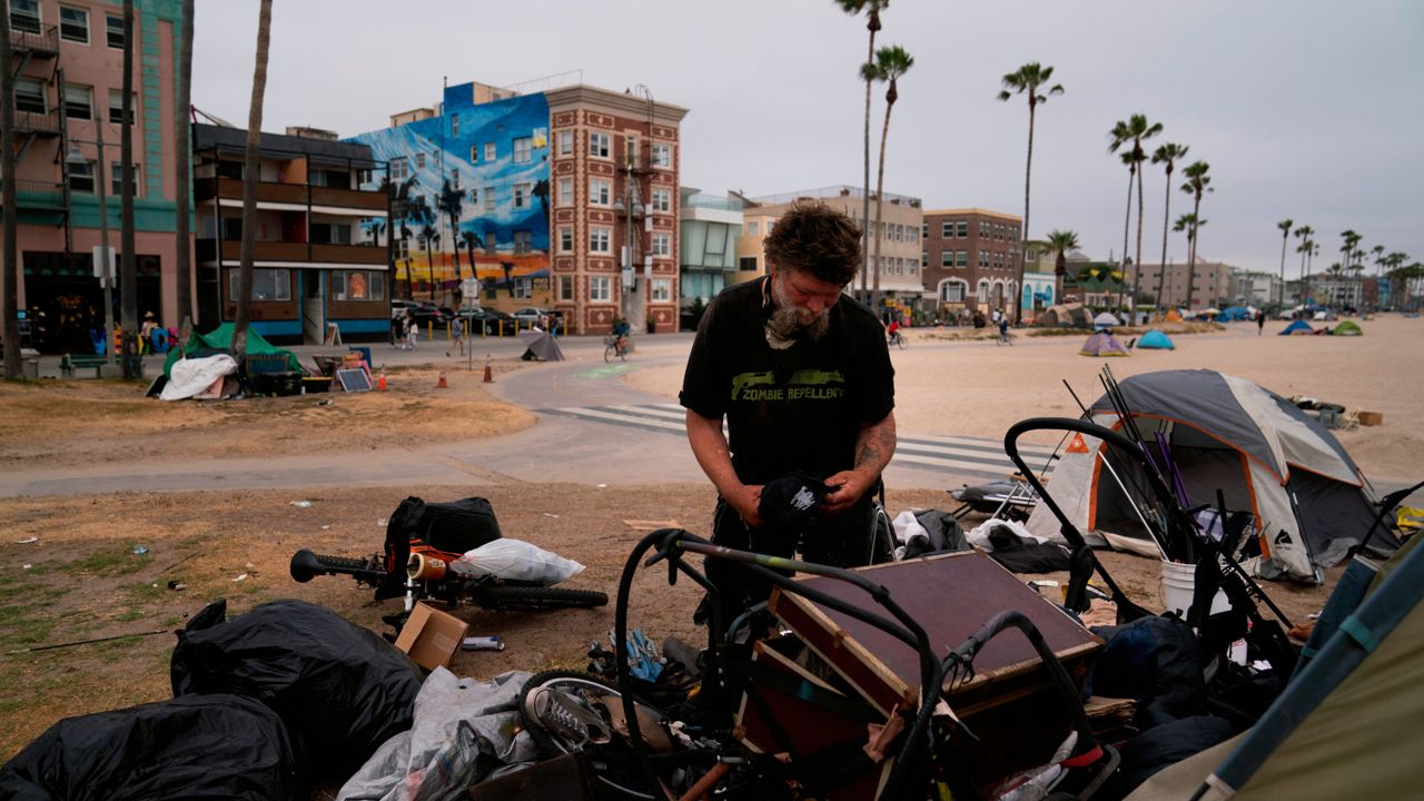 Jeremy Minney, a 43-year-old homeless man, sorts through his belongings in a homeless encampment set up along the boardwalk in the Venice neighborhood of Los Angeles, Tuesday, June 29, 2021. (AP Photo/Jae C. Hong)