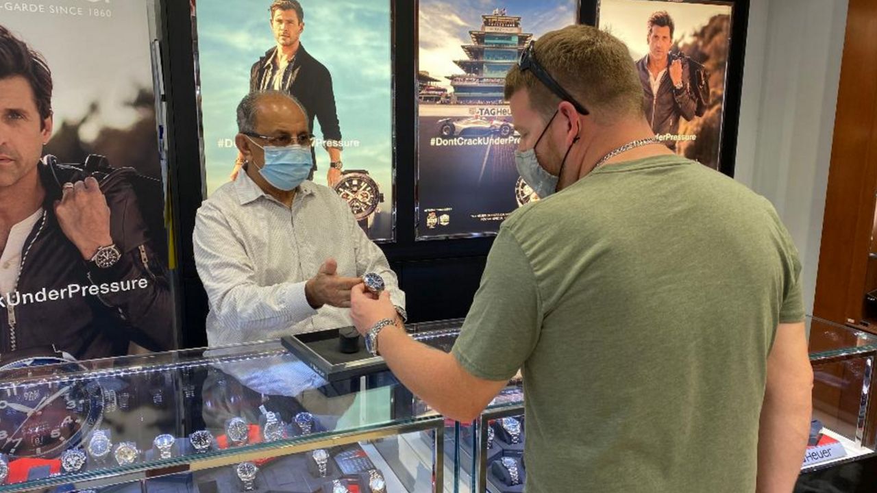 Abdul Tharoo shows a watch to customer Thomas King at his family-operated jewelry store near the Orange County Convention Center. (Pete Reinwald/Spectrum News 13)