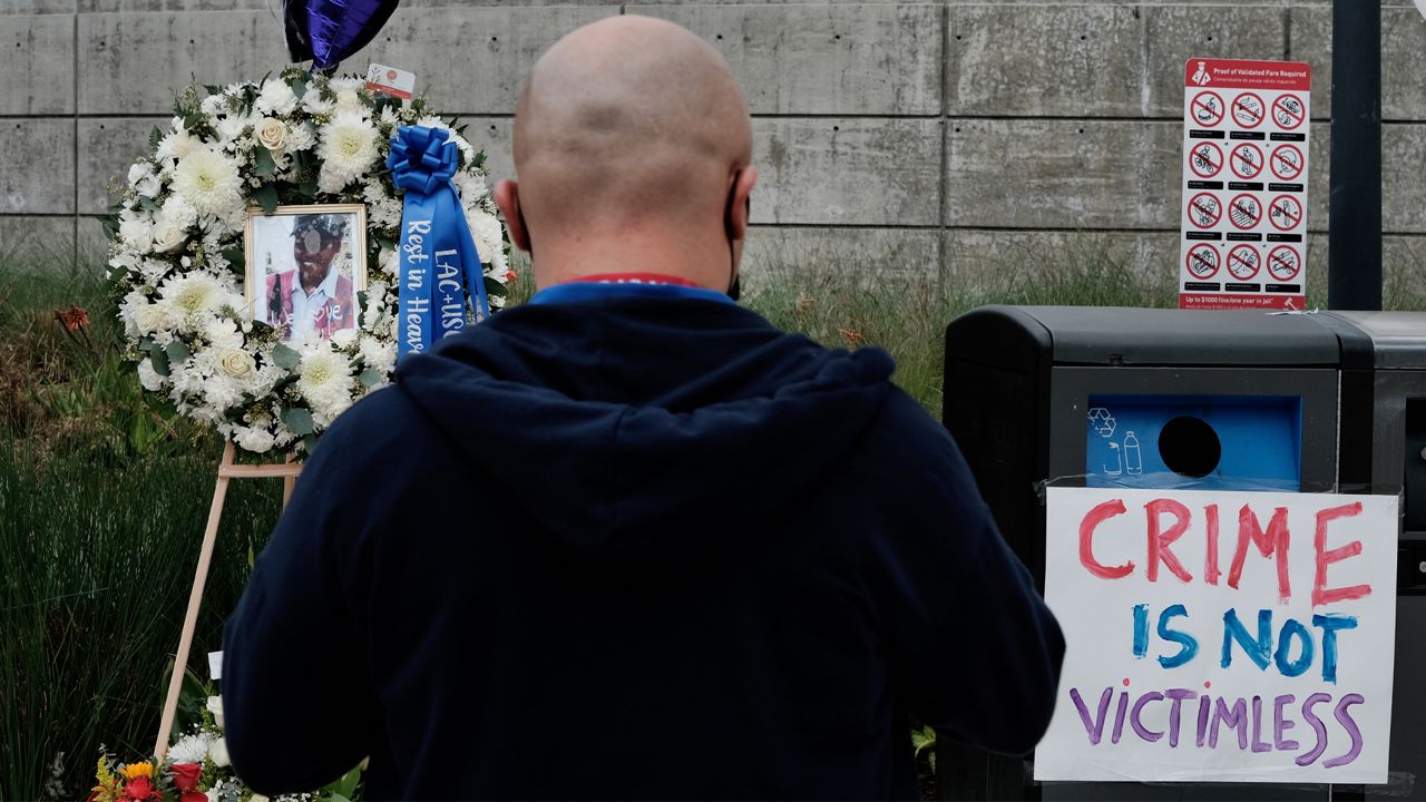 A passerby stops at a memorial for Nurse Sandra Shells at the bus stop on Jan. 19, 2022, in downtown Los Angeles, where Shells had been attacked. (AP Photo/Richard Vogel)