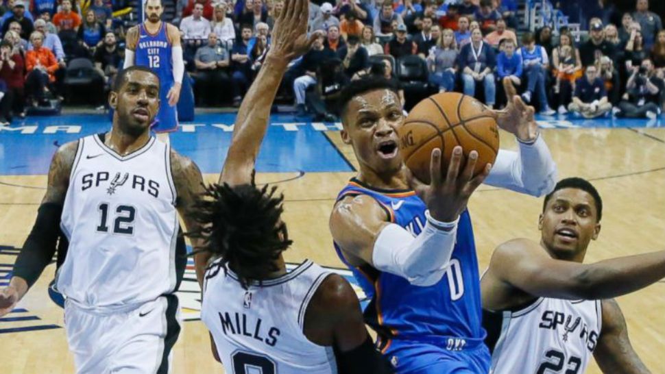 Oklahoma City Thunder guard Russell Westbrook (0) goes to the basket between San Antonio Spurs guard Patty Mills (8) and forward Rudy Gay (22) in the first half of an NBA basketball game in Oklahoma City, Saturday, March 10, 2018. (AP Photo/Sue Ogrocki)