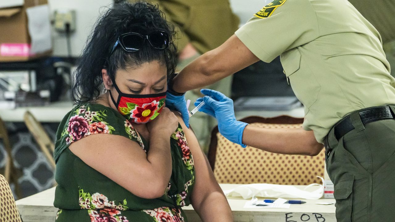 Los Angeles County Deputy Sheriff Emergency Medical Technician Deputy Brod, right, inoculates a woman with the Modern vaccine at a COVID-19 mobile vaccination clinic for Sheriff's employees at the Pomona Fairplex in Pomona, Calif., Friday, March 5, 2021. (AP Photo/Damian Dovarganes)