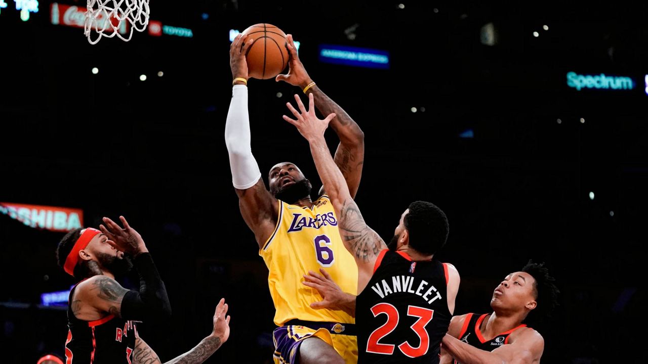 Los Angeles Lakers' LeBron James, center, left, goes up for a basket under pressure by Toronto Raptors' Fred VanVleet (23) during an NBA game Monday in LA. (AP Photo/Jae C. Hong)