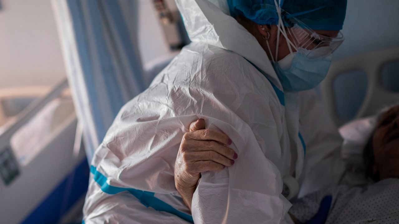 A coronavirus patient holds onto a nurse assistant
