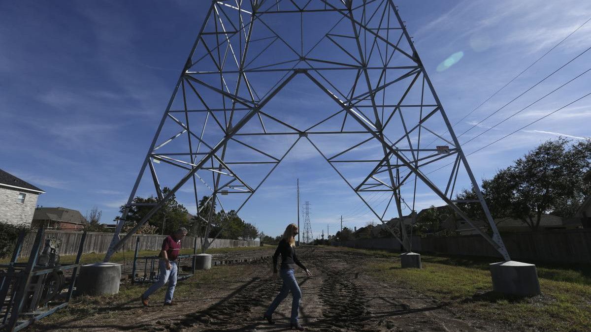 People walk near electricity tower (Yi-Chin Lee/Houston Chronicle via AP)
