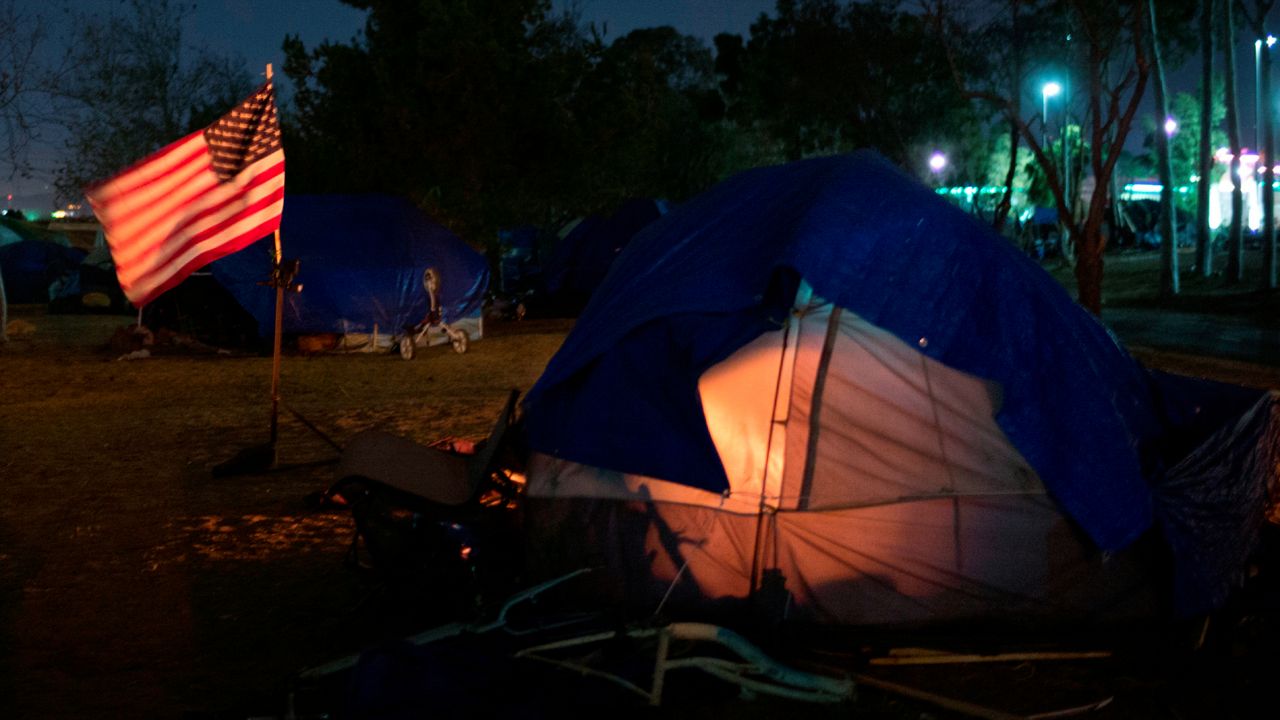 In this Dec. 10, 2017, file photo homeless tents are pitched around an America flag along the Santa Ana River trail in Anaheim, Calif. (AP Photo/Jae C. Hong, File)