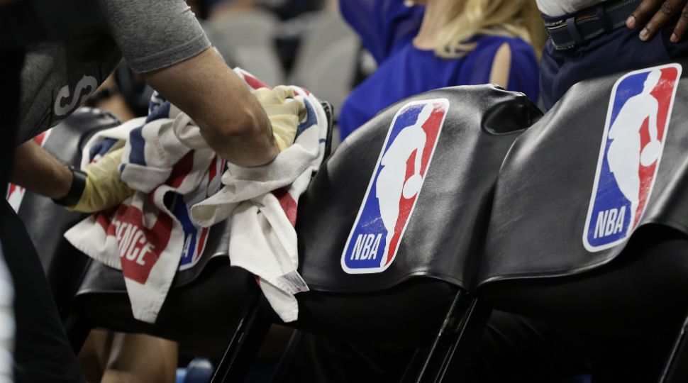 A team attendant uses protective gloves to wipe down seats in the players' bench area during an NBA basketball game between the San Antonio Spurs and the Dallas Mavericks in San Antonio, Tuesday, March 10, 2020. (AP Photo/Eric Gay)