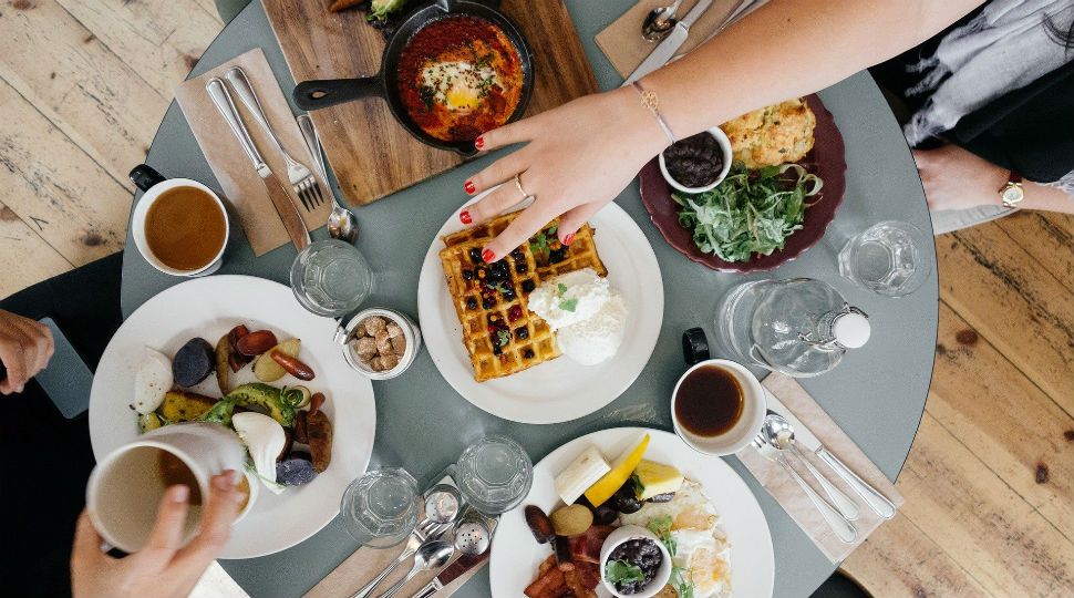 Hands reach out over a table of food and drinks (Stock image)