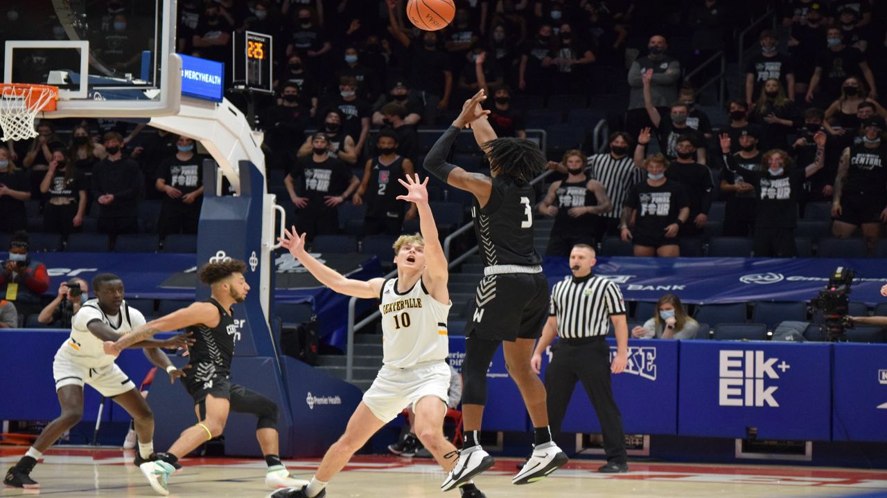 A basketball players shooting over a defender