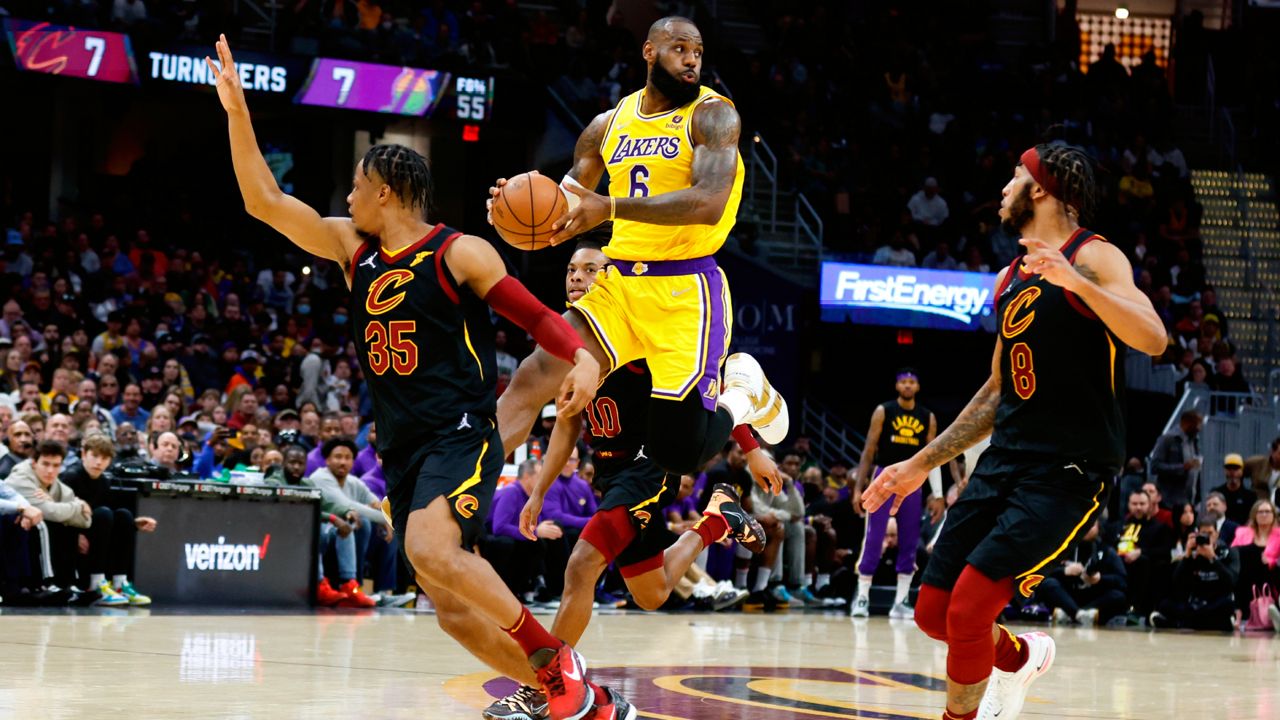 Los Angeles Lakers' LeBron James (6) passes the ball against Cleveland Cavaliers' Isaac Okoro (35) and Lamar Stevens (8) during the second half of an NBA basketball game, Monday, March 21, 2022, in Cleveland. (AP Photo/Ron Schwane)