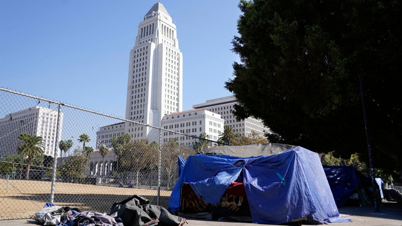 In this Oct. 28, 2020, file photo, a homeless person's tent stands just outside Grand Park with Los Angeles City Hall in the background in Los Angeles. (AP Photo/Chris Pizzello, File)