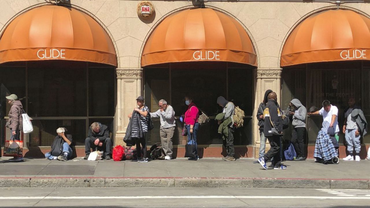 People line up outside GLIDE, a charity that offers free meals, a shelter and other services to the homeless, Friday, March 20, 2020, in San Francisco. As California authorities said they were working to limit the spread of the coronavirus in the homeless population, homeless people congregated as usual in parks and on sidewalks, despite orders to stay 6 feet apart and practice social distancing. (AP Photo/Juliet Williams)