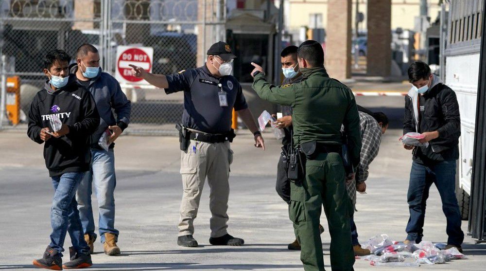U.S. Customs and Border Protection officers, center, instruct migrants to walk toward the McAllen-Hidalgo International Bridge while deporting them to Mexico, Saturday, March 20, 2021, in Hidalgo, Texas.  (AP Photo/Julio Cortez)