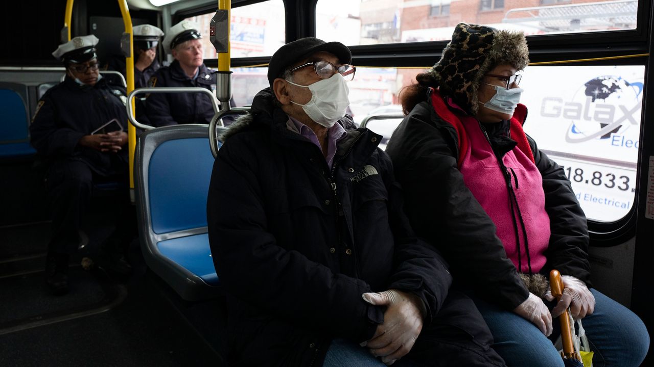 People wearing masks and sitting on a bus