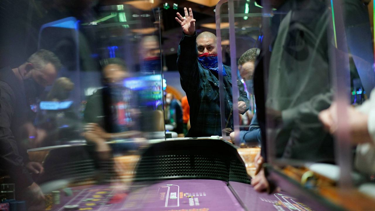 People play craps while wearing masks and between plexiglas partitions as a precaution against the coronavirus at the opening night of the Mohegan Sun Casino at Virgin Hotels Las Vegas on March 25, 2021. (AP Photo/John Locher)