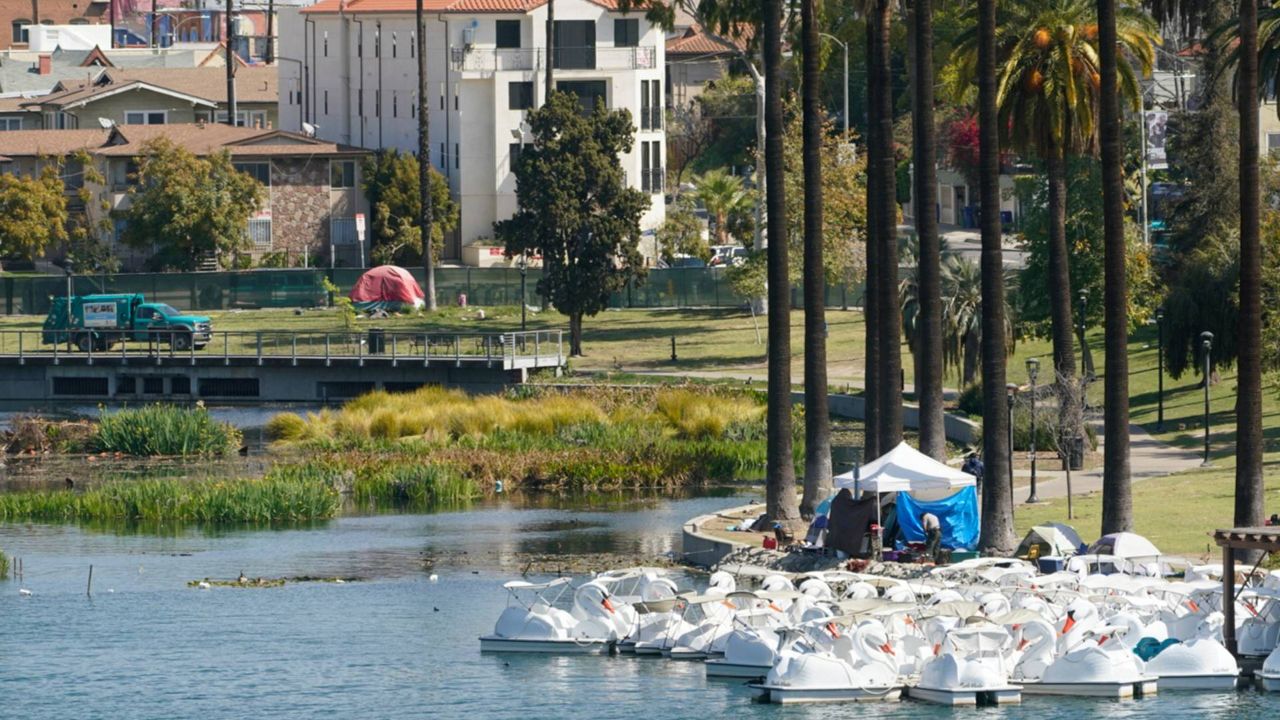 Los Angeles City Park Ranger walks around tents set by the Boat House on the east side of Echo Park Lake in LA, March 26, 2021. (AP Photo/Damian Dovarganes)