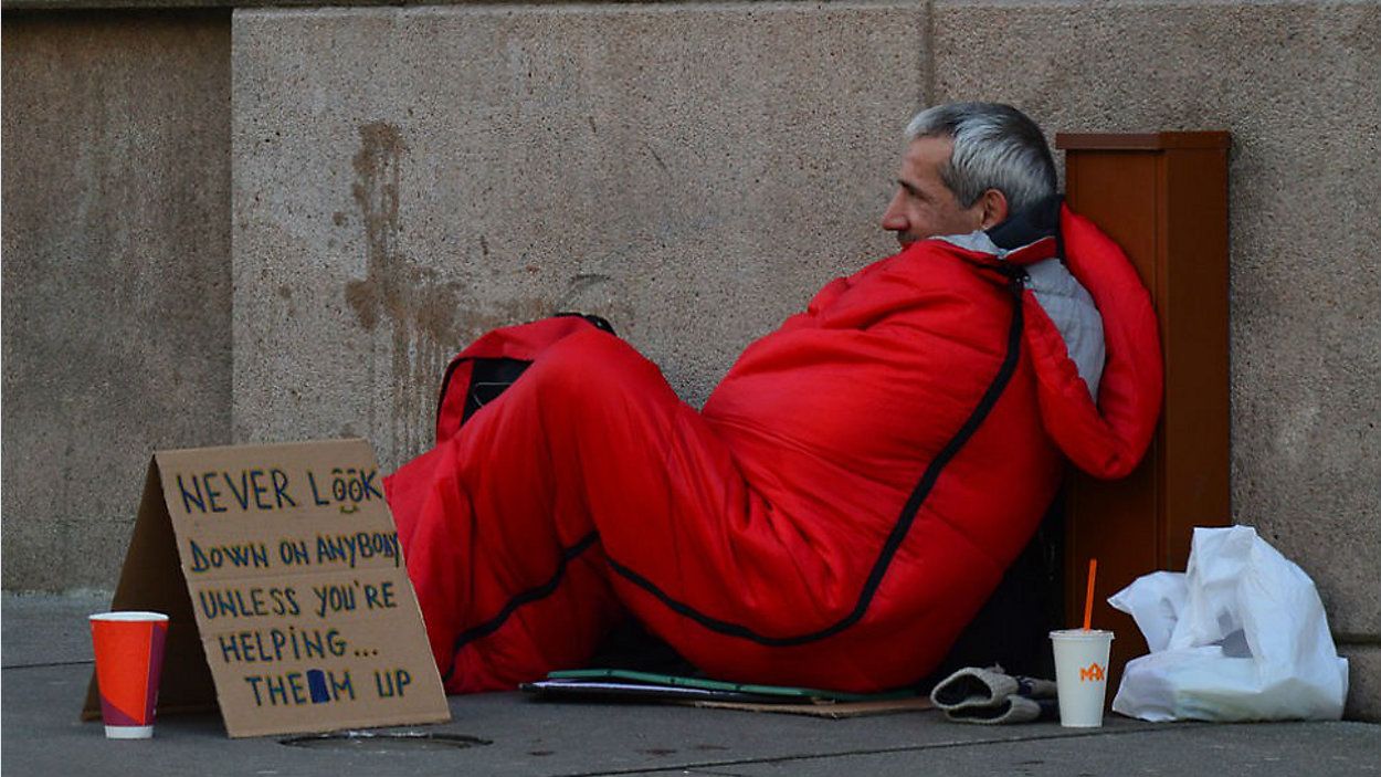 FILE photo of a homeless man with a sign that says "Never look down on anybody unless you're helping them up." (Pixabay)