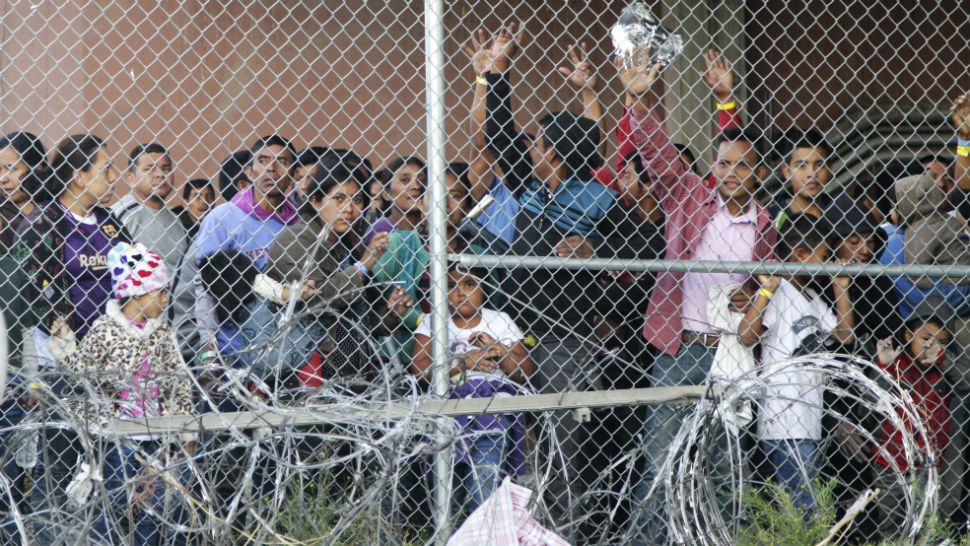 Central American migrants wait for food in El Paso, Texas, Wednesday, March 27, 2019, in a pen erected by U.S. Customs and Border Protection to process a surge of migrant families and unaccompanied minors. Earlier, Customs and Border Protection Commissioner Kevin McAleenan, center, announced the the Trump administration will temporarily reassign several hundred border inspectors, during a news conference at the border in El Paso. (AP Photo/Cedar Attanasio)