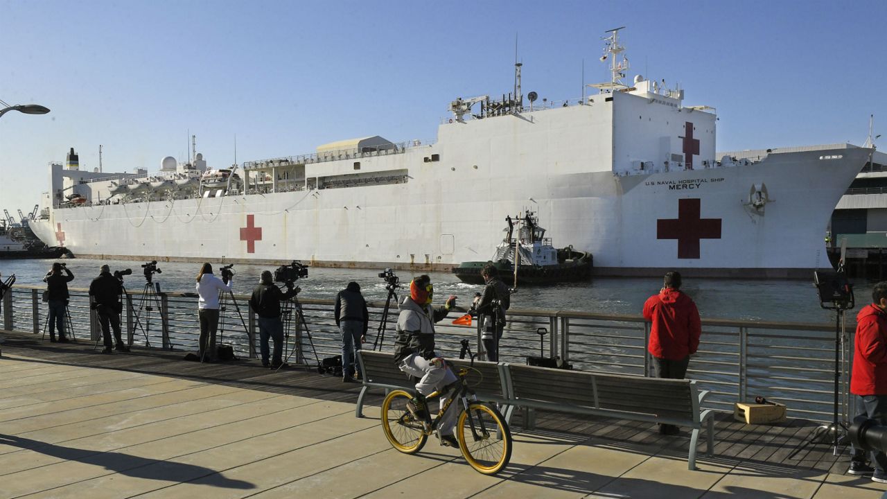 A cyclist rides by as the USNS Mercy docks the Port of Los Angeles, Friday, March 27, 2020, in Los Angeles. The The 1,000-bed Navy hospital ship is expected to help take the load off Los Angeles area hospitals as they treat coronavirus patients. The new coronavirus causes mild or moderate symptoms for most people, but for some, especially older adults and people with existing health problems, it can cause more severe illness or death. (AP Photo/Mark J. Terrill)
