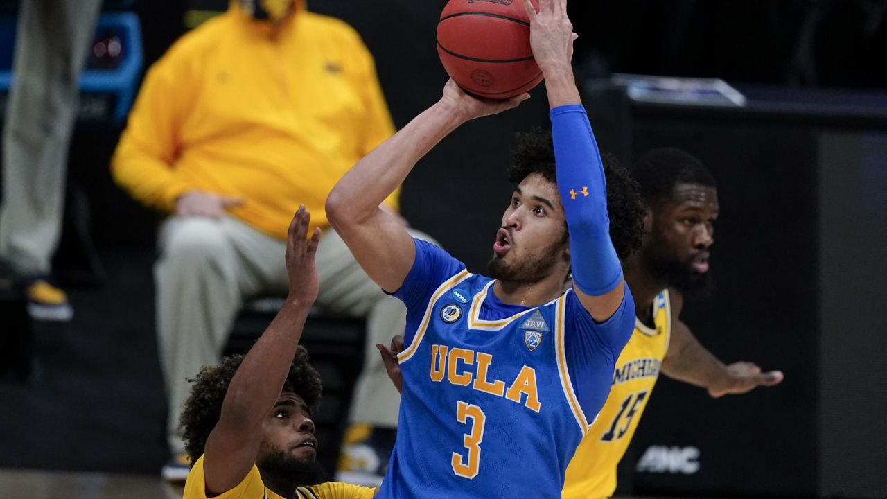 UCLA guard Johnny Juzang (3) shoots over Michigan guard Mike Smith, left, during the first half of an Elite 8 game in the NCAA men's college basketball tournament at Lucas Oil Stadium, Tuesday, March 30, 2021, in Indianapolis. (AP Photo/Michael Conroy)