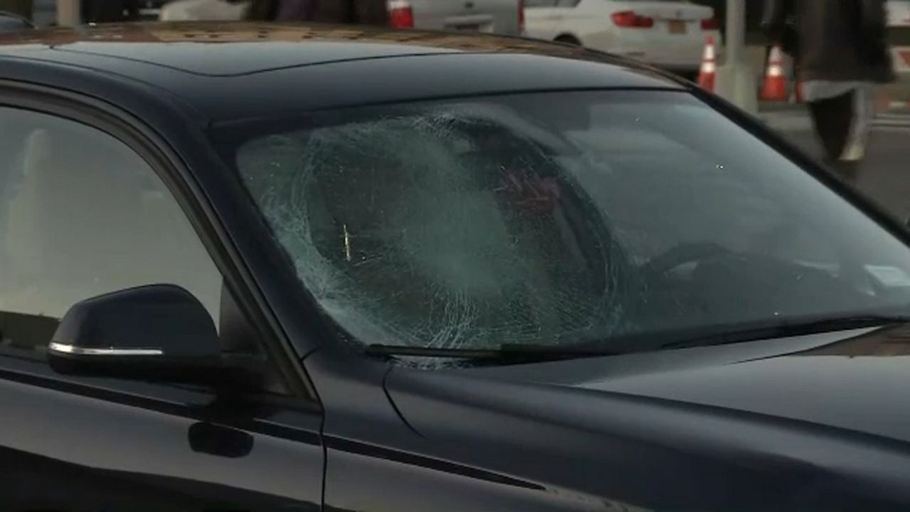 A black car's window is smashed on the front passenger's ride of the windshield.