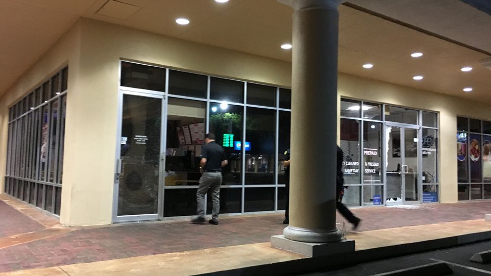 Owner Raul Caite looks into the smashed front window of his restaurant, Jersey Mike's Subs on Conroy Road in Orlando, early Friday morning. He told Spectrum News 13 that nothing was stolen. Two other stores were smashed into as well. (Anthony Leone, staff)