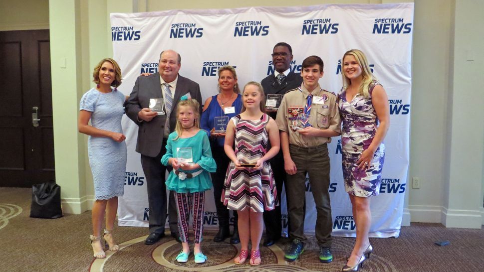 Spectrum News 13 anchor and co-hostess Ybeth Bruzual, left, stands with Everyday Hero winners (from left), Russ Durham, Sarah Lewis, Shannon Vetter, Faith-Christina Duncan, Howard Gentry, Elijah Kelly, and Spectrum News reporter and co-hostess Erin Murray. (Anthony Leone, staff)                        