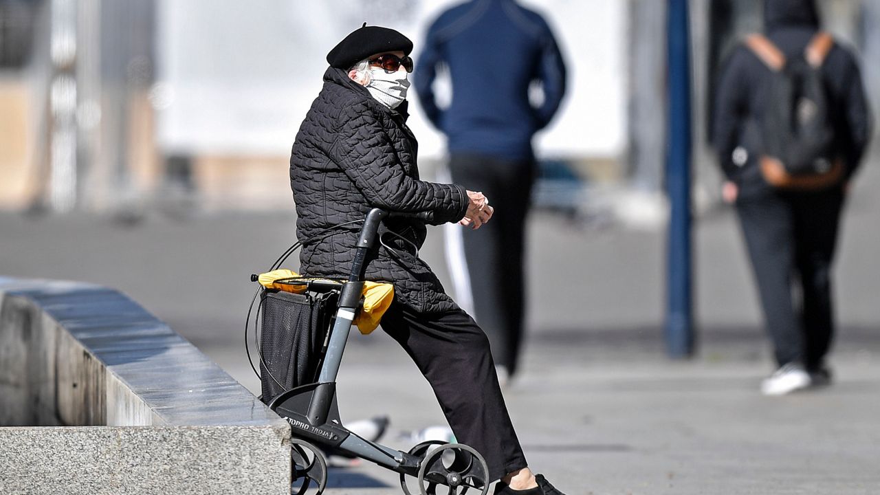 Photo of an elderly woman wearing a mask in public (AP Images)