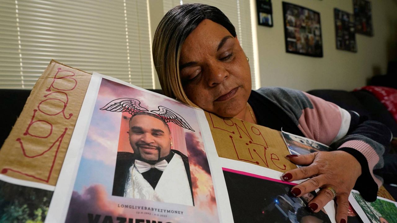 Penelope Scott holds a collection of family photos including one of her son, De'vazia Turner, one of the victims killed in a mass shooting, during an interview with The Associate Press in Elk Grove, Calif., Monday. (AP Photo/Rich Pedroncelli)