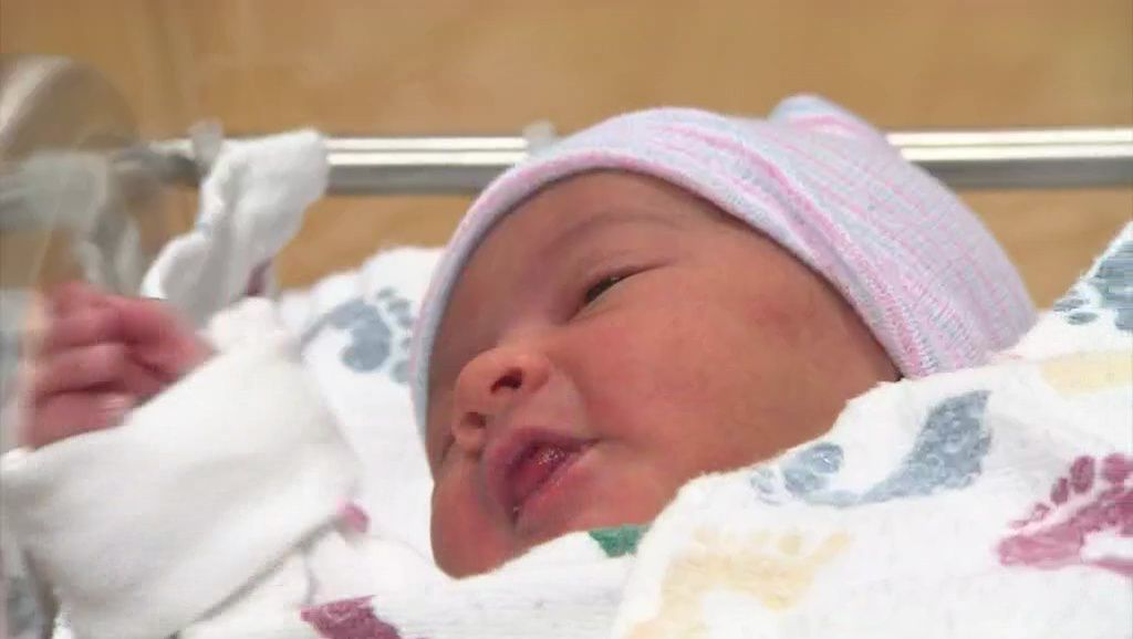 A newborn lays in a hospital nursery.