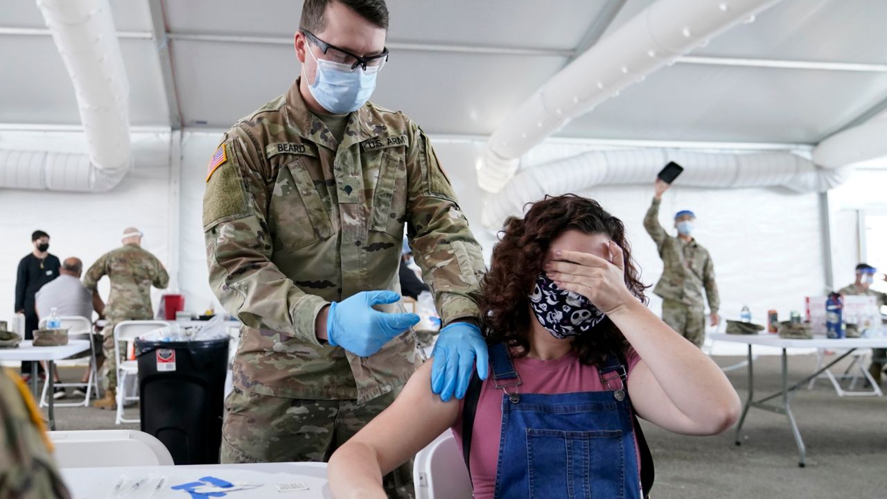 In this photo from Monday, April 5, 2021, Leanne Montenegro, 21, covers her eyes as she receives the Pfizer COVID-19 vaccine at a FEMA vaccination center at Miami Dade College. Florida by far leads the nation in the number of recorded cases of coronavirus variants. (Lynne Sladky/AP)