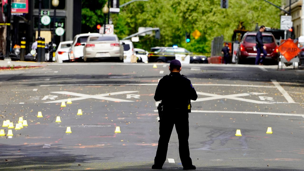 A Sacramento City Police Officer stands near a field of evidence markers after a mass shooting In Sacramento, Calif. April 3, 2022. (AP Photo/Rich Pedroncelli)