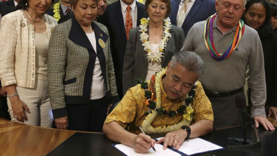 John Radcliffe, right, who was diagnosed with cancer in 2014, watches as Hawaii Gov. David Ige signs a bill to lwgalize medically assisted suicide on Thursday, April 5, 2018 in Honolulu. Radcliffe testified in favor of the measure and said Thursday he was happy it passed. Doctors in the state can now fulfill requests from terminally ill patients to prescribe life-ending medication. Hawaii is the sixth U.S. state, plus Washington D.C., to legalize the practice. (AP Photo/Sophia Yan)