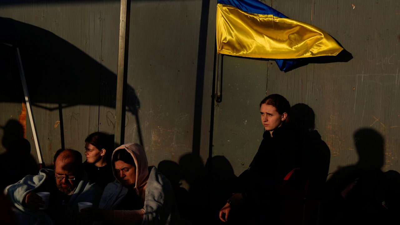 Ukrainian refugees wait near the U.S. border Monday, April 4, 2022, in Tijuana, Mexico. (AP Photo/Gregory Bull)