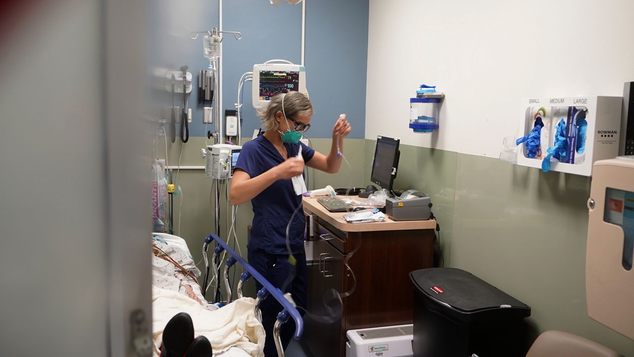 Registered nurse Sandra Younan sets up a new intravenous line for a patient under her care at Providence Cedars-Sinai Tarzana Medical Center in the Tarzana neighborhood of Los Angeles on Thursday, March 11, 2021. (AP Photo/Damian Dovarganes)
